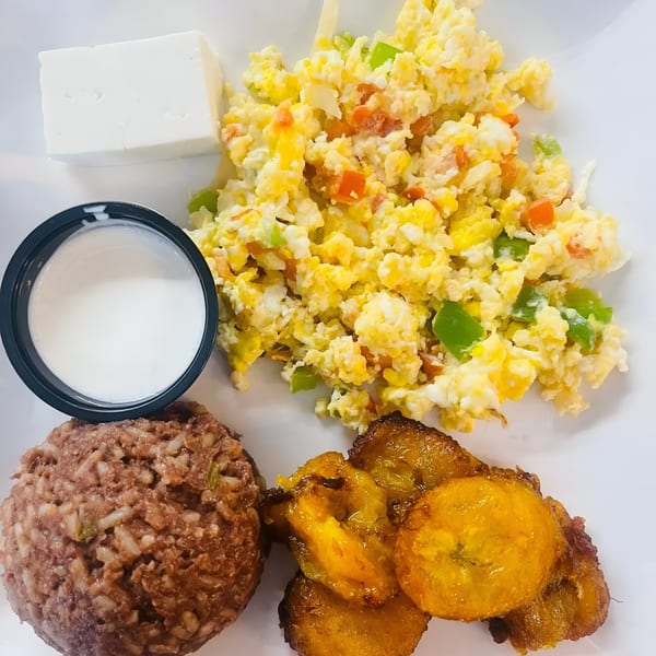 A Salvadoran breakfast plate with scrambled eggs, fried plantains, rice and beans, cheese, and cream.